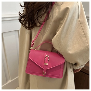 Close-up of fuchsia leather square bag with gold metal buckle on a trench coat model