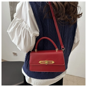 Detail of red crossbody bag with gold chain lock and glossy leather texture