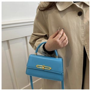 Detail view of bright cyan leather handbag featuring a gold metallic clasp and top handle