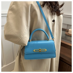 Close-up of sky blue fashion crossbody bag with golden metal buckle and smooth leather