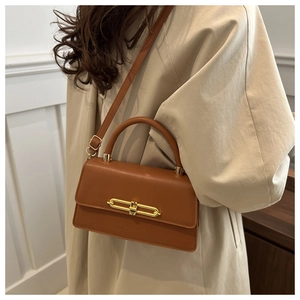 Detail of caramel leather shoulder bag with a gold chain lock and top handle