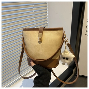Detail view of canvas bucket bag with brown leather trim and cute plush sheep charm