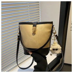 Detail of contrast bucket bag featuring canvas texture and golden twist lock closure