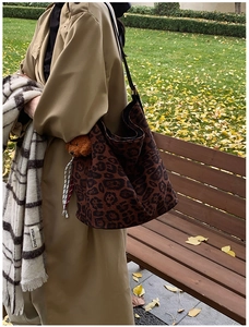Detailed shot of leopard print tote bag with brown plush bear charm in autumn setting