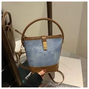 Detail of blue denim and brown leather bucket bag with a golden metal lock closure
