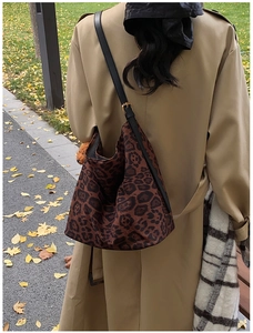 Detail of large leopard print tote bag with black leather strap on trench coat