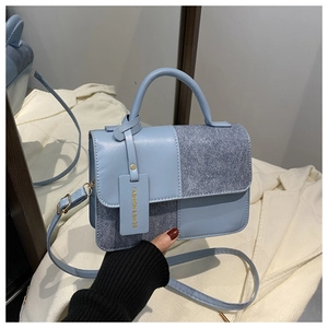 Detail of light blue crossbody bag featuring smooth leather and glitter patchwork design