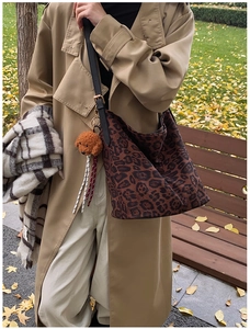 Outdoor lifestyle shot of a leopard print tote bag with a teddy bear charm in autumn
