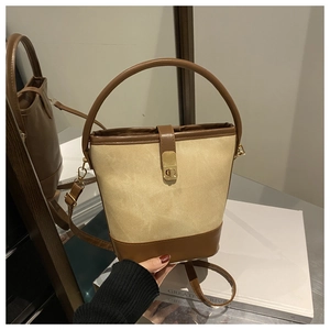 Detail shot of vintage bucket bag with beige canvas and brown leather patchwork and gold lock