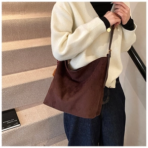 Close-up of caramel suede tote bag featuring a leather strap and orange plush ball charm