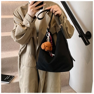 Close-up of black canvas tote bag with metal buckle and cute brown teddy dog plush charm