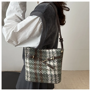 Detail of vintage plaid wool shoulder bag with leather straps and metal buckle accent