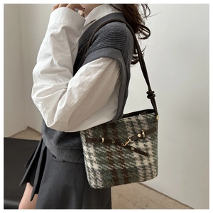 Detail of green and white tweed bucket bag with brown leather trim and golden buckle