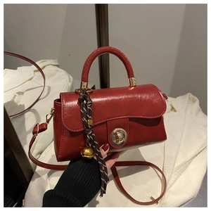 Detail view of red leather handbag with gold twist lock and striped scarf accessory
