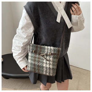 Detail of vintage plaid tweed bucket bag with leather trim on model outfit