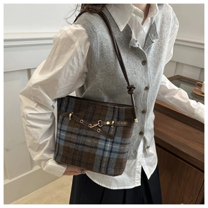 Detail of checkered bucket bag featuring brown leather straps and gold metal hardware