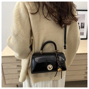 Chic black vintage satchel with silk scarf handle detail worn by a model in soft lighting