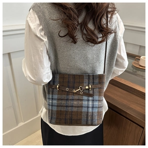 Close-up of vintage plaid bucket bag with brown leather strap and gold buckle detail