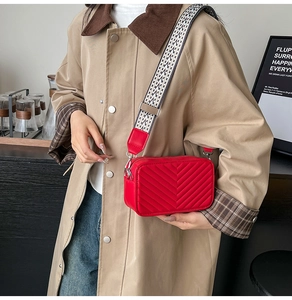 Détail du sac bandoulière rouge matelassé avec surpiqûres en V et sangle géométrique