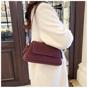Detail view of the wine red frosted suede texture and flap design on the shoulder bag