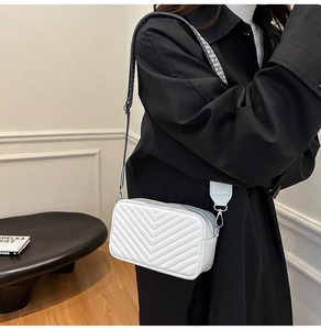 Détail du sac bandoulière blanc matelassé avec une large sangle géométrique chic