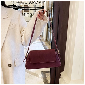 Close-up of burgundy frosted suede shoulder bag with adjustable side strap details
