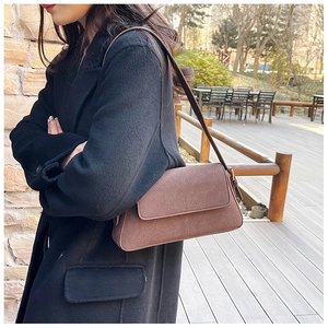 Detail showing brown frosted leather shoulder bag with adjustable strap and flap closure