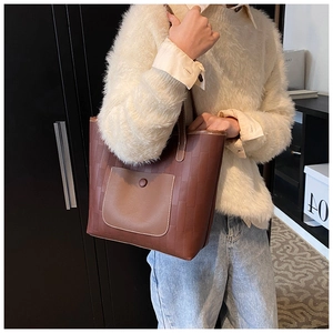Detail of the brown tote bag featuring textured brick pattern leather and contrast pocket