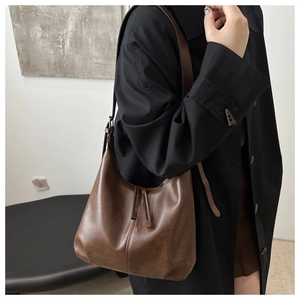 Detail of a brown PU leather hobo shoulder bag with a decorative fringe tassel and stitching