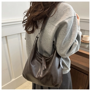 Deep brown leather shoulder bag shown on model featuring adjustable strap and minimalist style