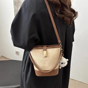 Retro canvas bucket bag with brown leather trim and plush charm shown on model