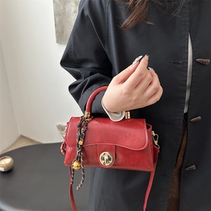 Vintage red oil wax leather handbag for women featuring gold hardware and a tassel charm