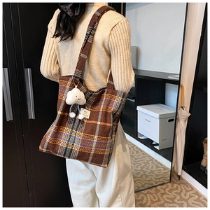 Brown vintage checkered tote bag with a white plush cloud charm shown on a shoulder