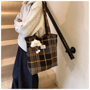 Detail of vintage plaid tote bag featuring a plush cloud charm and retro checkered pattern