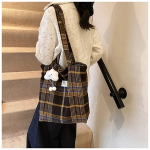 Close-up of vintage plaid tote bag with cloud charm and woven texture details