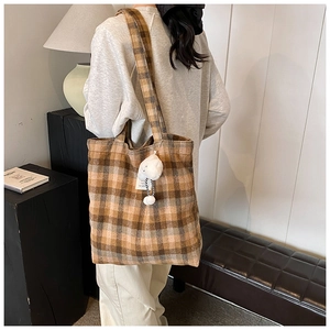 Detail shot of the vintage plaid tote bag featuring a plush charm and shoulder straps