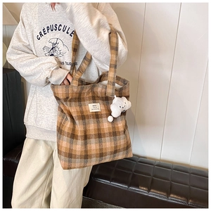 Detail of a brown plaid canvas tote bag with a cute white cloud plush charm pendant