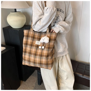 Large plaid wool tote bag with cloud charm detail shown on model in a modern room