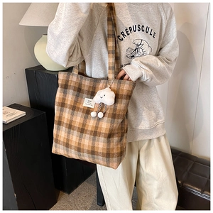 Detailed close-up of brown checkered canvas tote bag with cute cloud plush charm