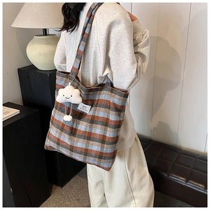 Detail view of large checkered tote bag with a white plush cloud charm and label