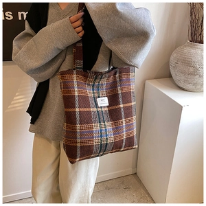 Detail of checkered tweed tote bag featuring brand label and thick woven texture