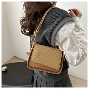 Detail of camel shoulder bag featuring embossed diamond texture and knotted strap design