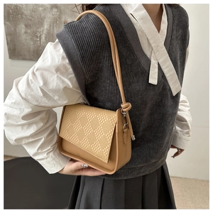 Detail of camel shoulder bag with woven texture flap and knotted strap on model