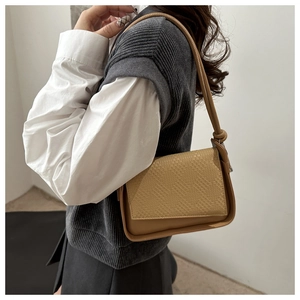 Close-up of brown crossbody bag featuring intricate woven texture and leather strap