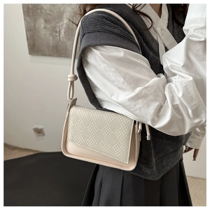 Detail of cream woven leather handbag featuring intricate checkered texture and knotted strap