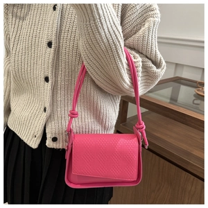 Detail of a bright pink woven texture handbag with creative knot strap on shoulder