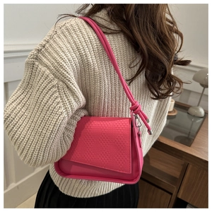 Detail of pink shoulder bag with woven texture on beige sweater and black skirt
