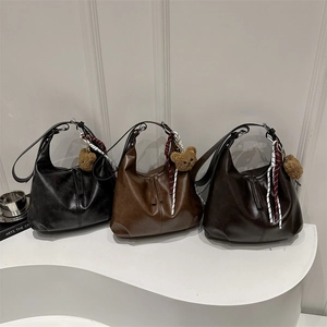 Three minimalist hobo tote bags in black, caramel, and brown with cute plush bear charms