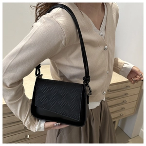 Detail showing woven texture flap and knot strap of the black structured shoulder bag