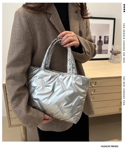Detail of silver metallic quilted tote bag with vertical textured patterns and sturdy handle